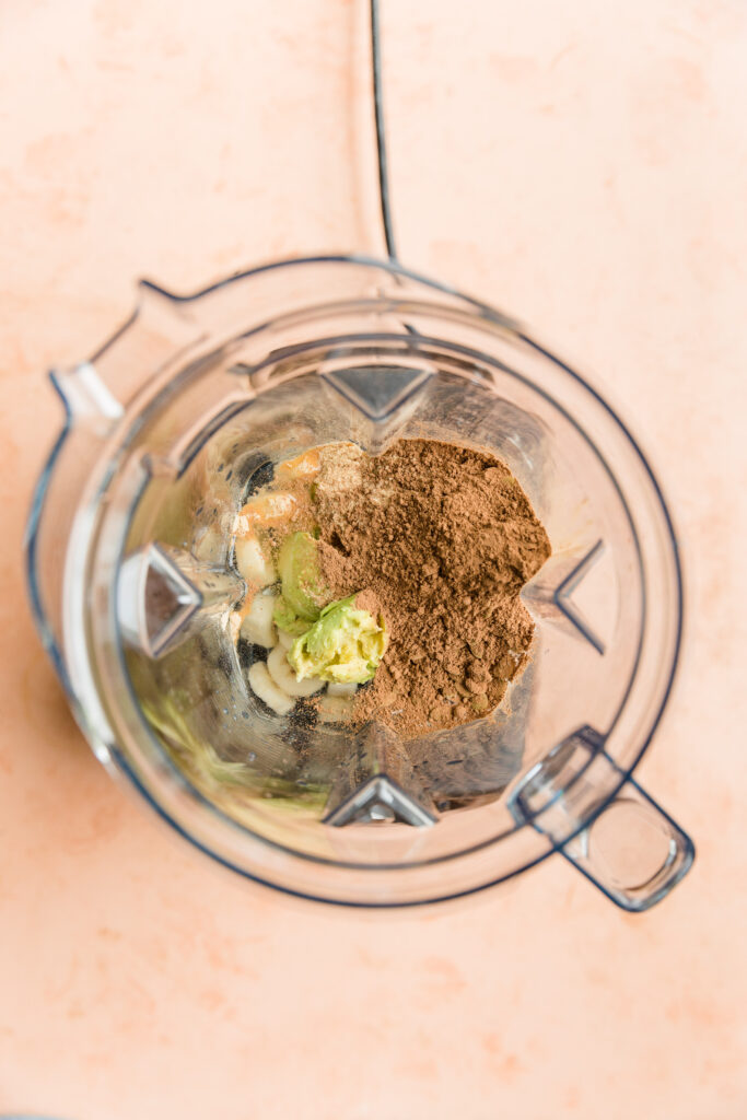 Ingredients for creamy chocolate protein shake in blender.