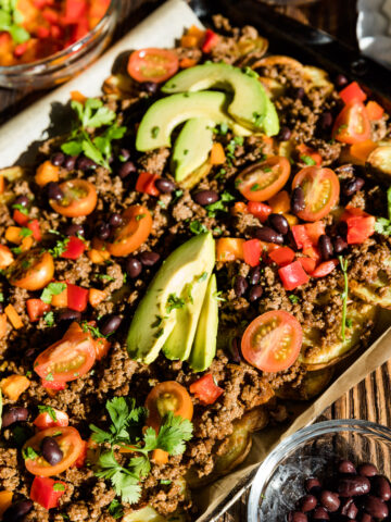 Potato nachos with tomato, bell peppers, black beans, and avocado on top.
