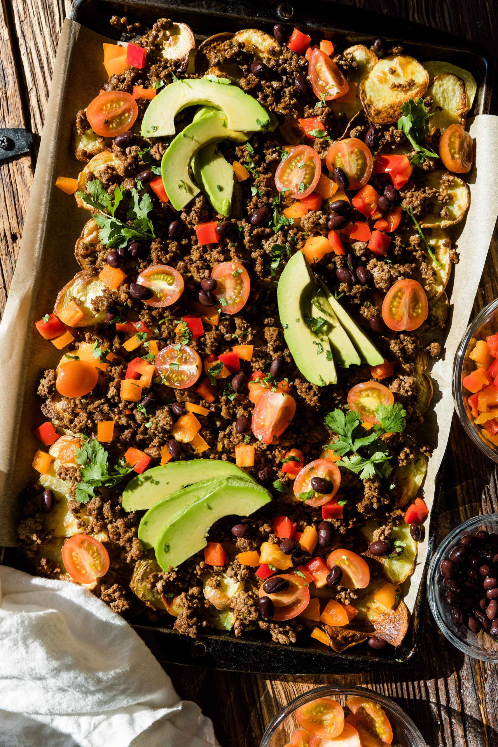 Potato nachos with ground beef and fresh vegetables on top.
