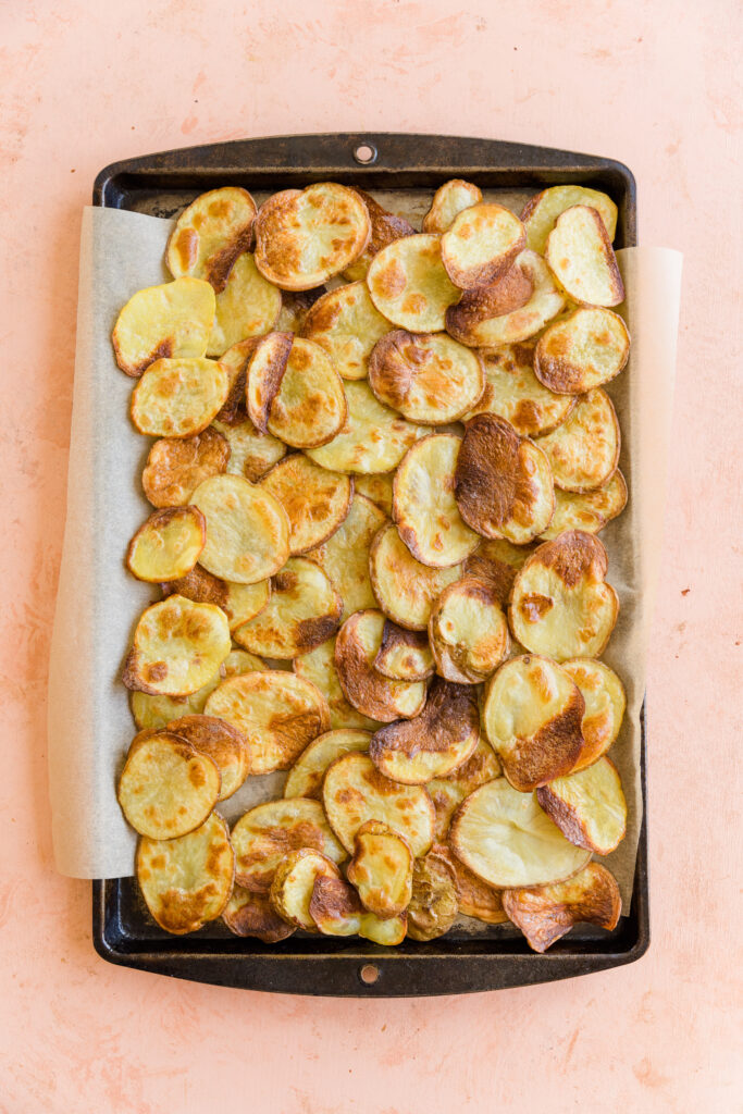 Crispy potato discs layered on a sheet pan.