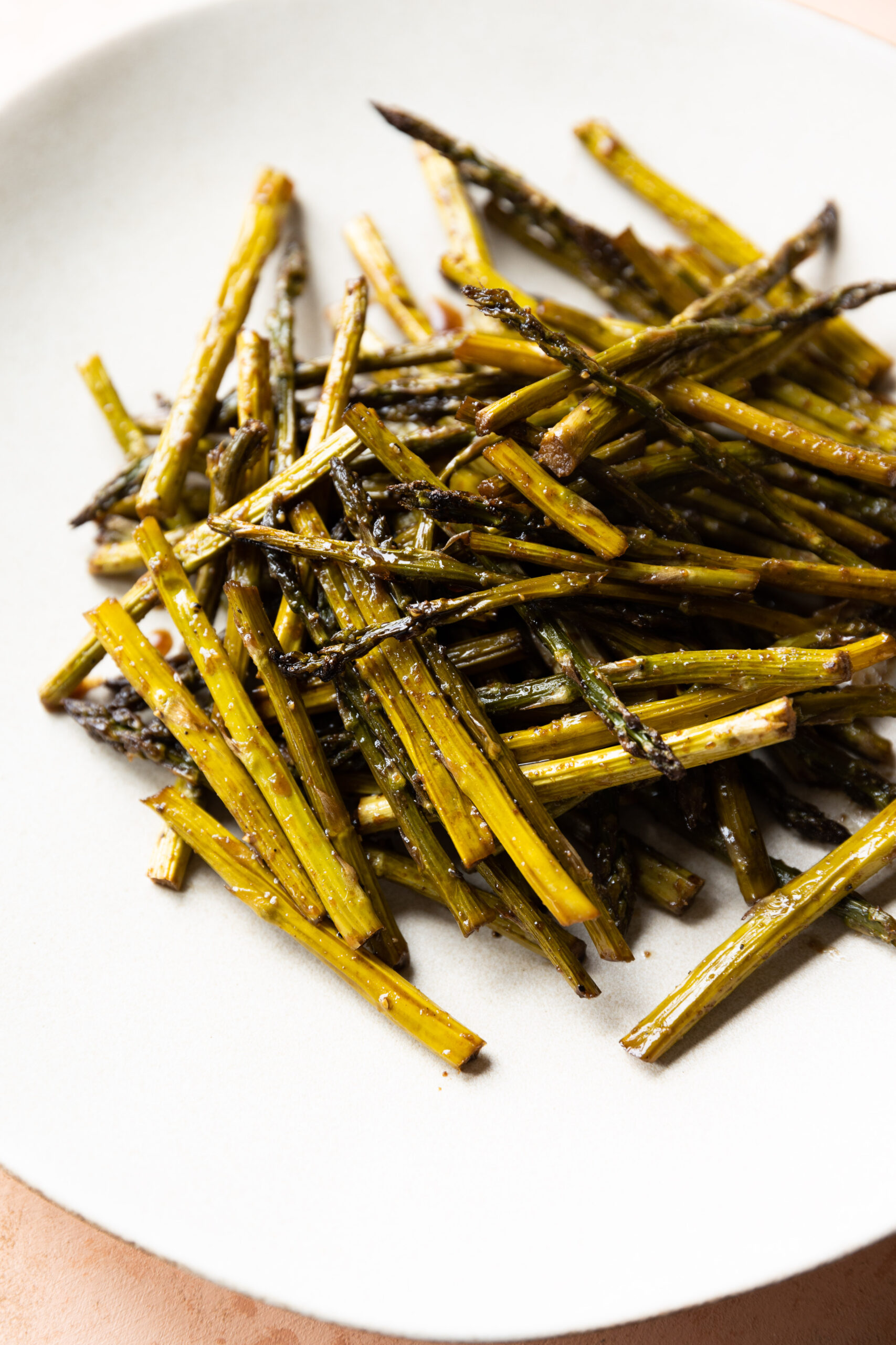 Roasted asparagus piled up on a serving plate.