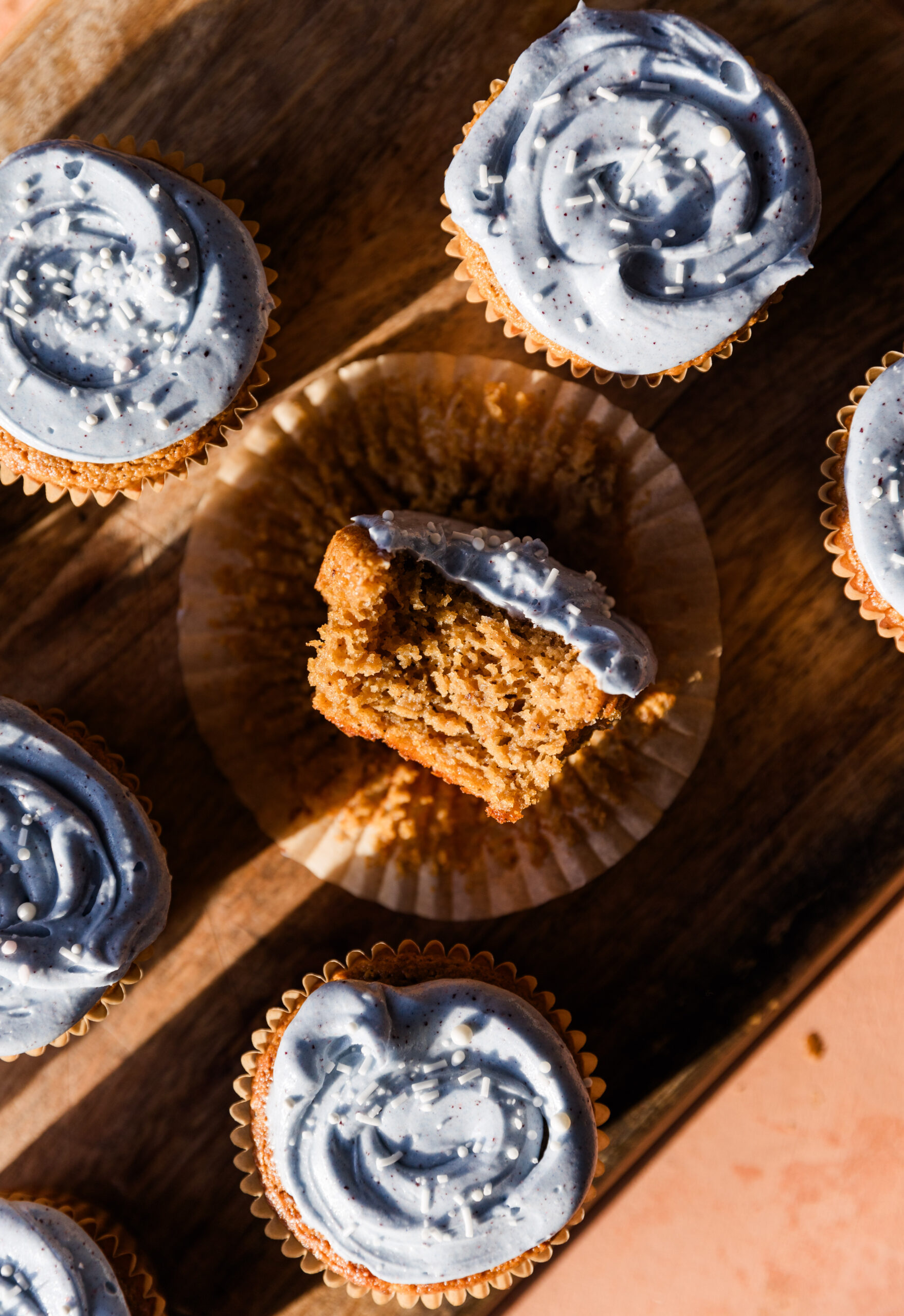 Big bite taken out of gluten free vanilla cupcake with blue frosting.