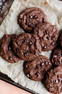 Overhead picture of double chocolate chip cookies on a parchment paper lined baking sheet.