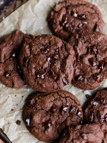 Gluten-Free double chocolate chip cookies on parchment paper with melted chocolate chips on top.