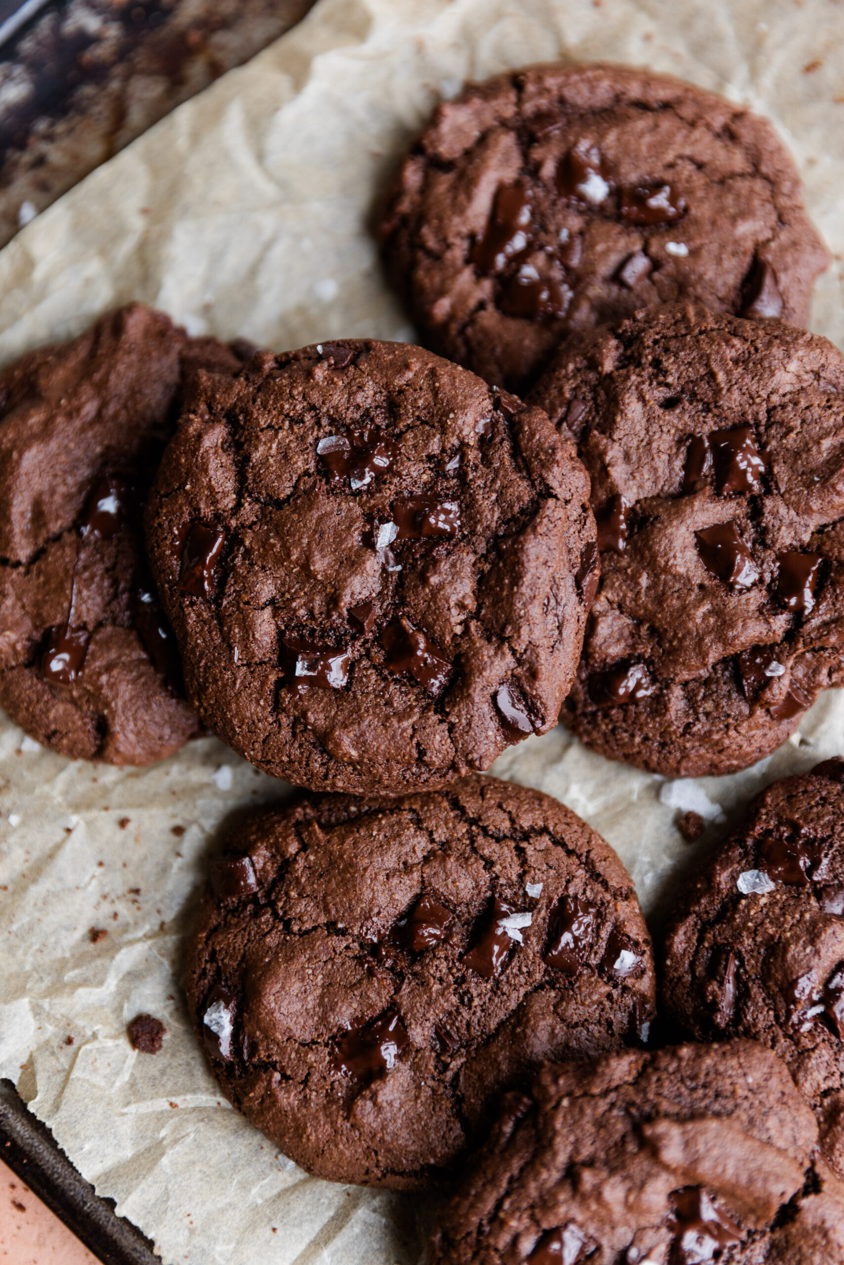 Gluten-Free double chocolate chip cookies on parchment paper with melted chocolate chips on top.