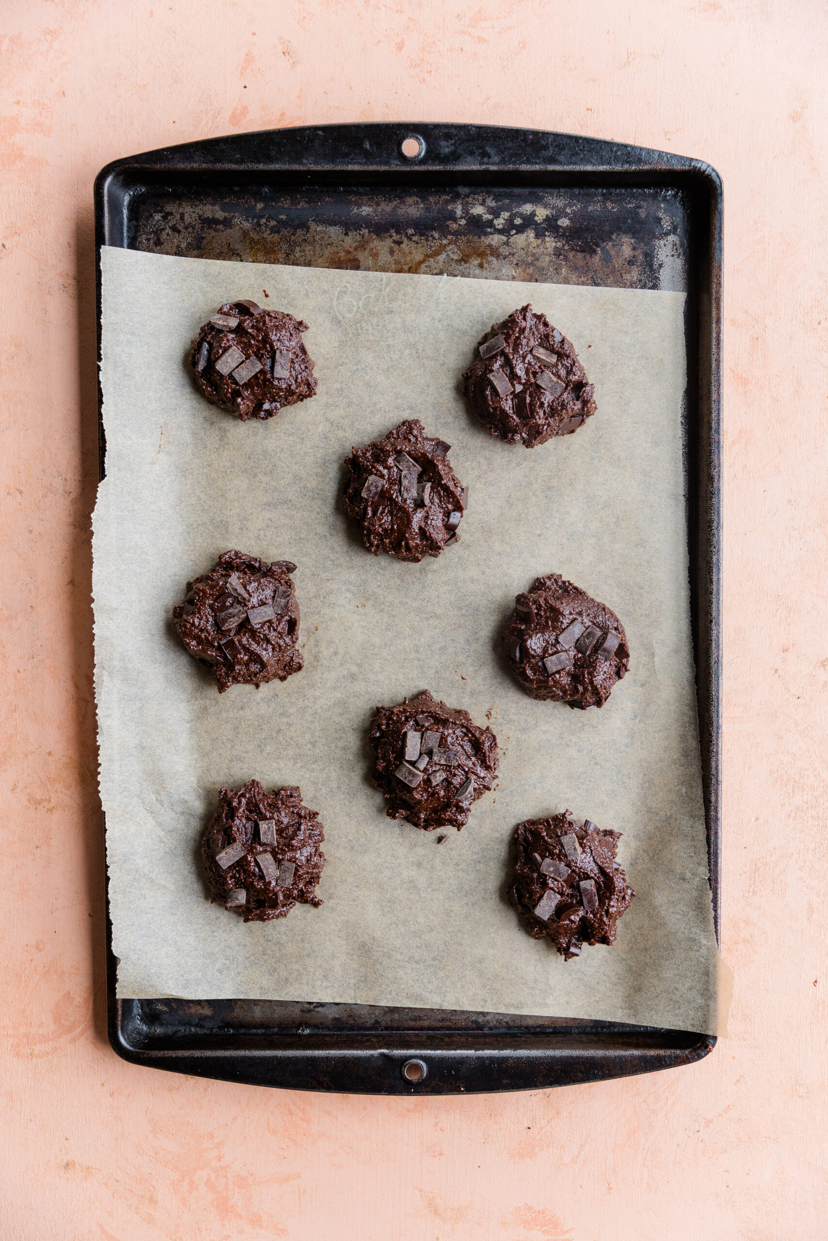 Cookie dough balls on a parchment paper lined baking sheet.