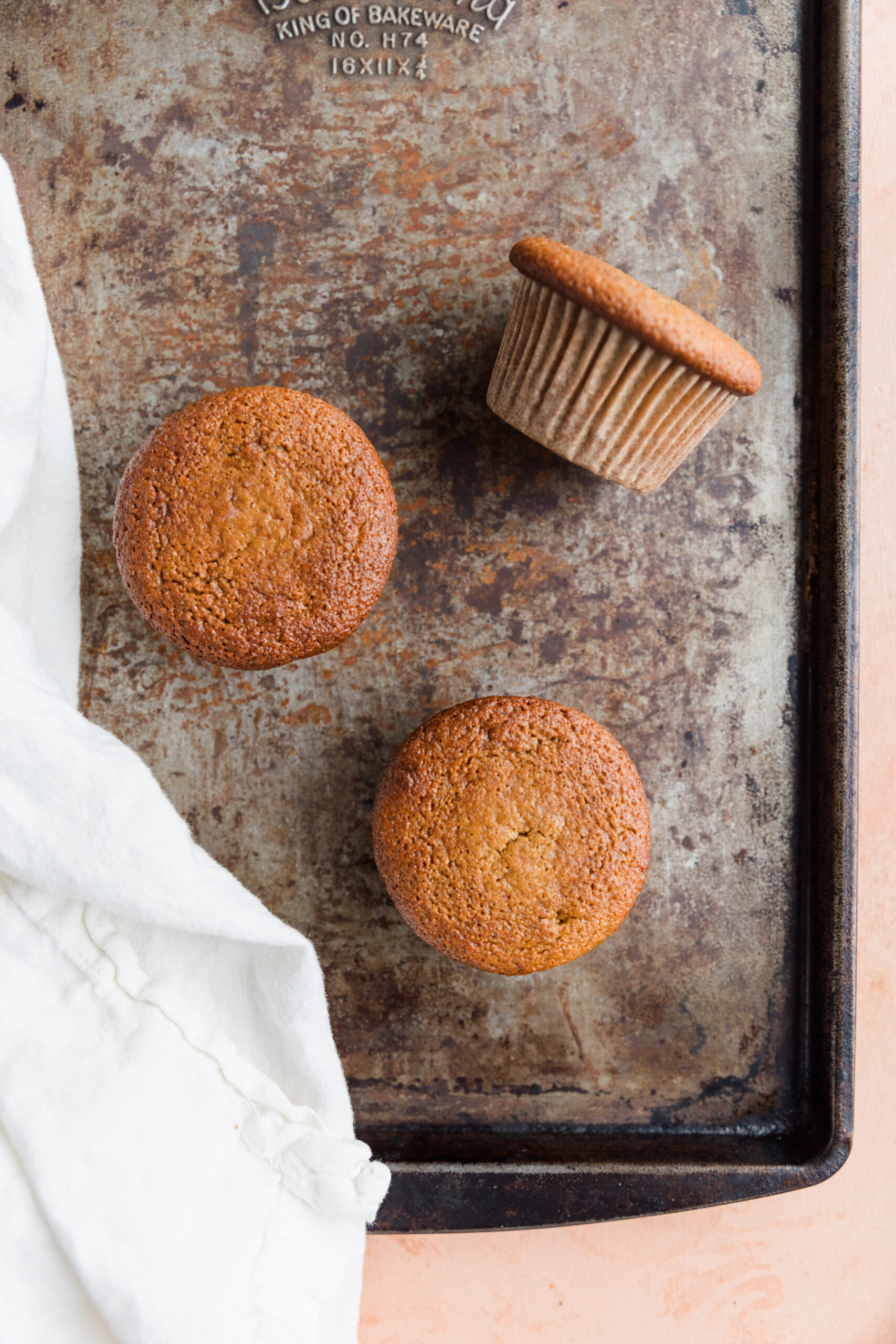 Three vanilla cupcakes on a baking sheet.