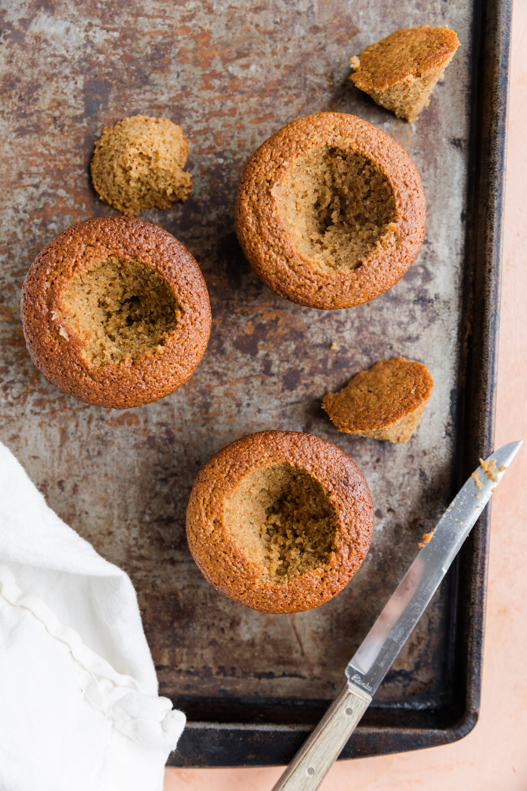 Three vanilla cupcakes with a small hole cut in the center.