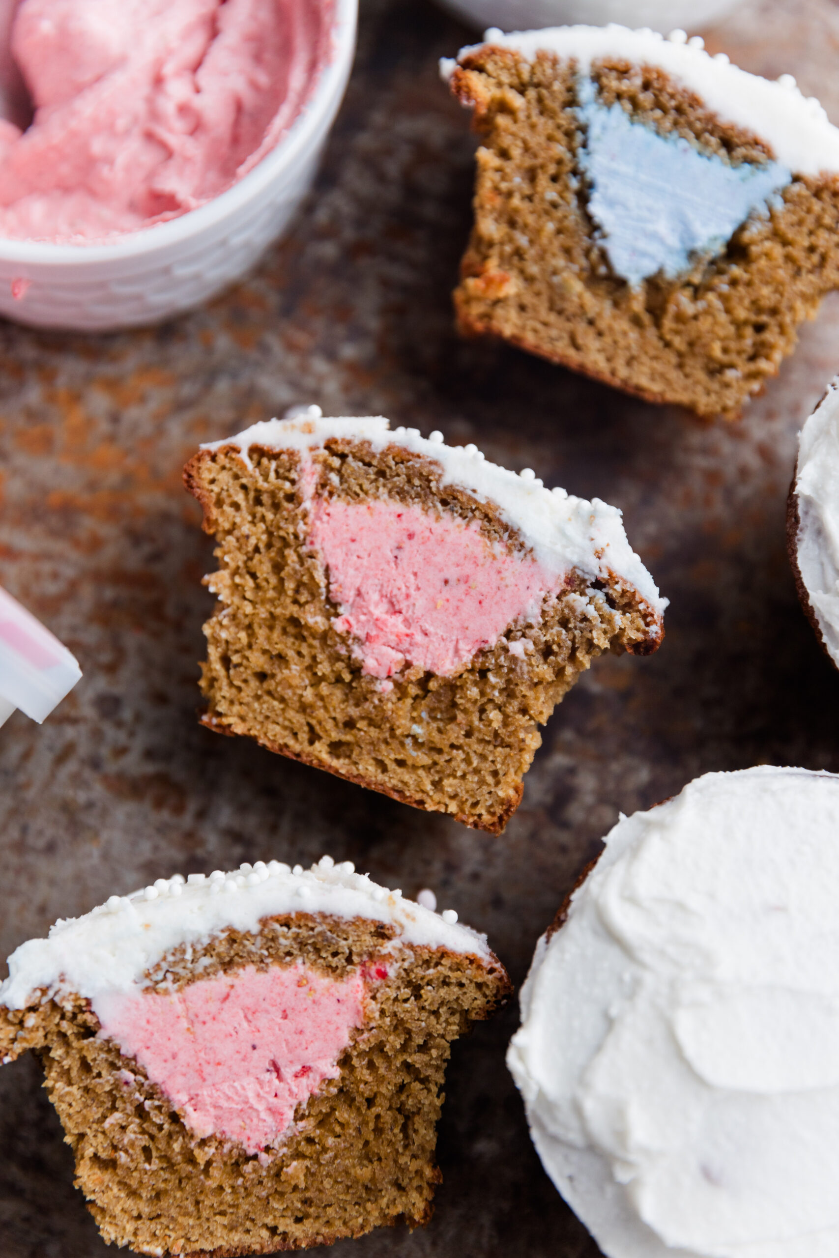 Pink and blue gender reveal cupcakes cut in half with frosting in the center.