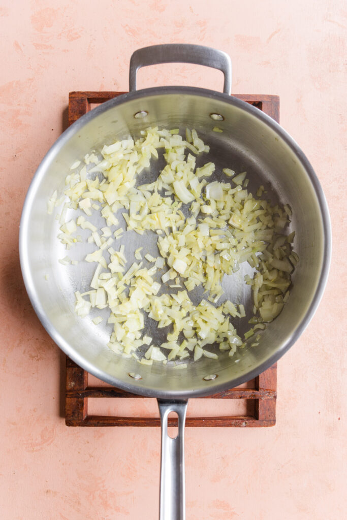 Diced onions cooking in large pan.
