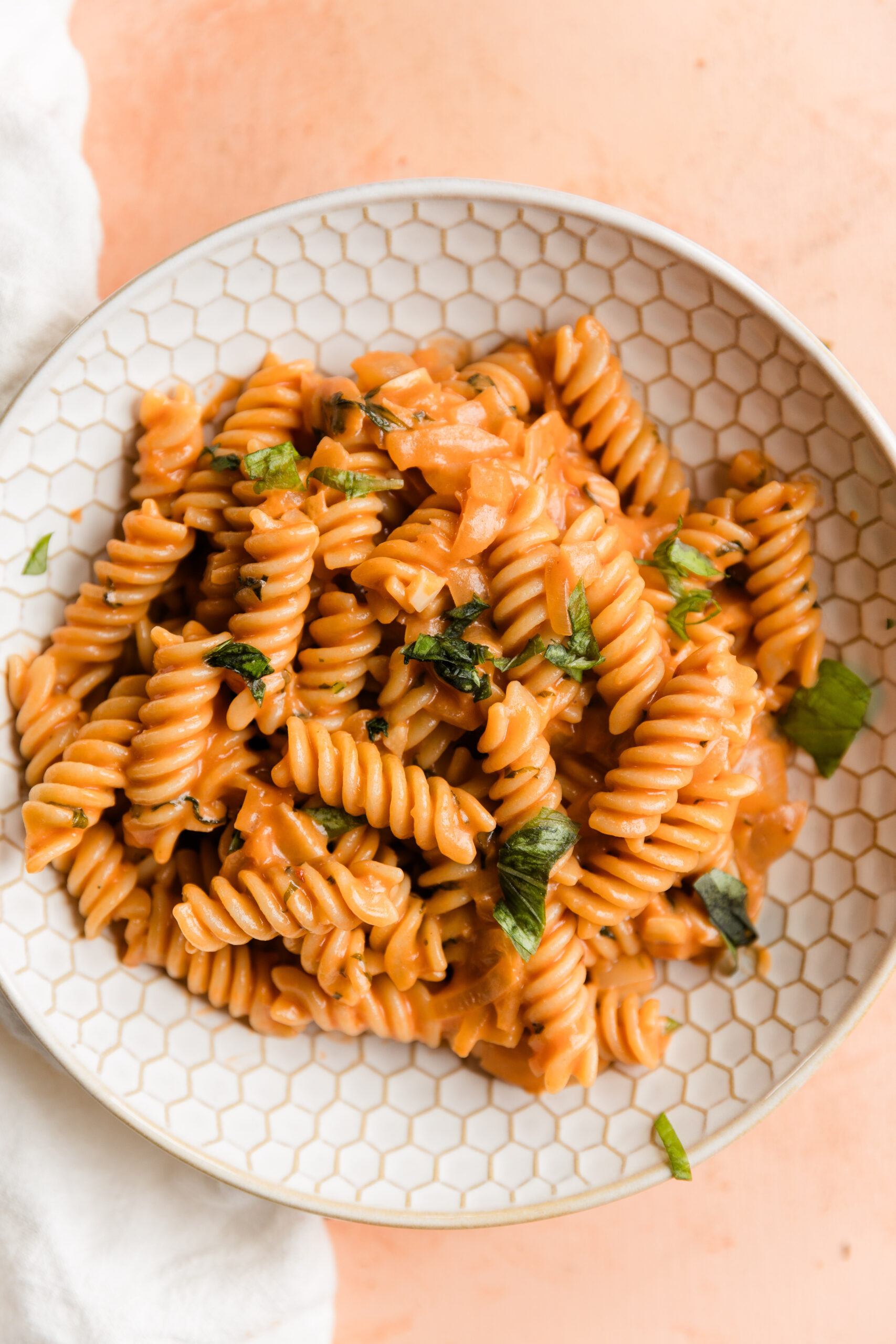 Big bowl of fusilli gluten-free pasta with vegan pink sauce.