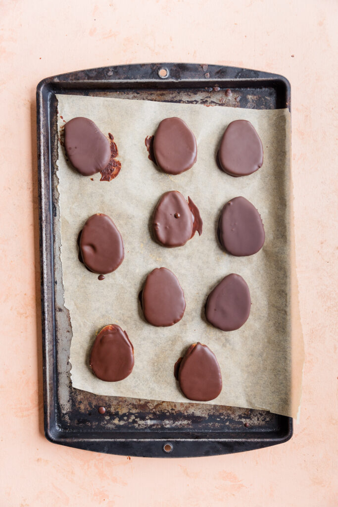 Chocolate dipped eggs on a parchment paper lined baking sheet.