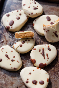 White chocolate covered copycat healthier Reece's eggs on a baking sheet with dark chocolate drizzled on top.