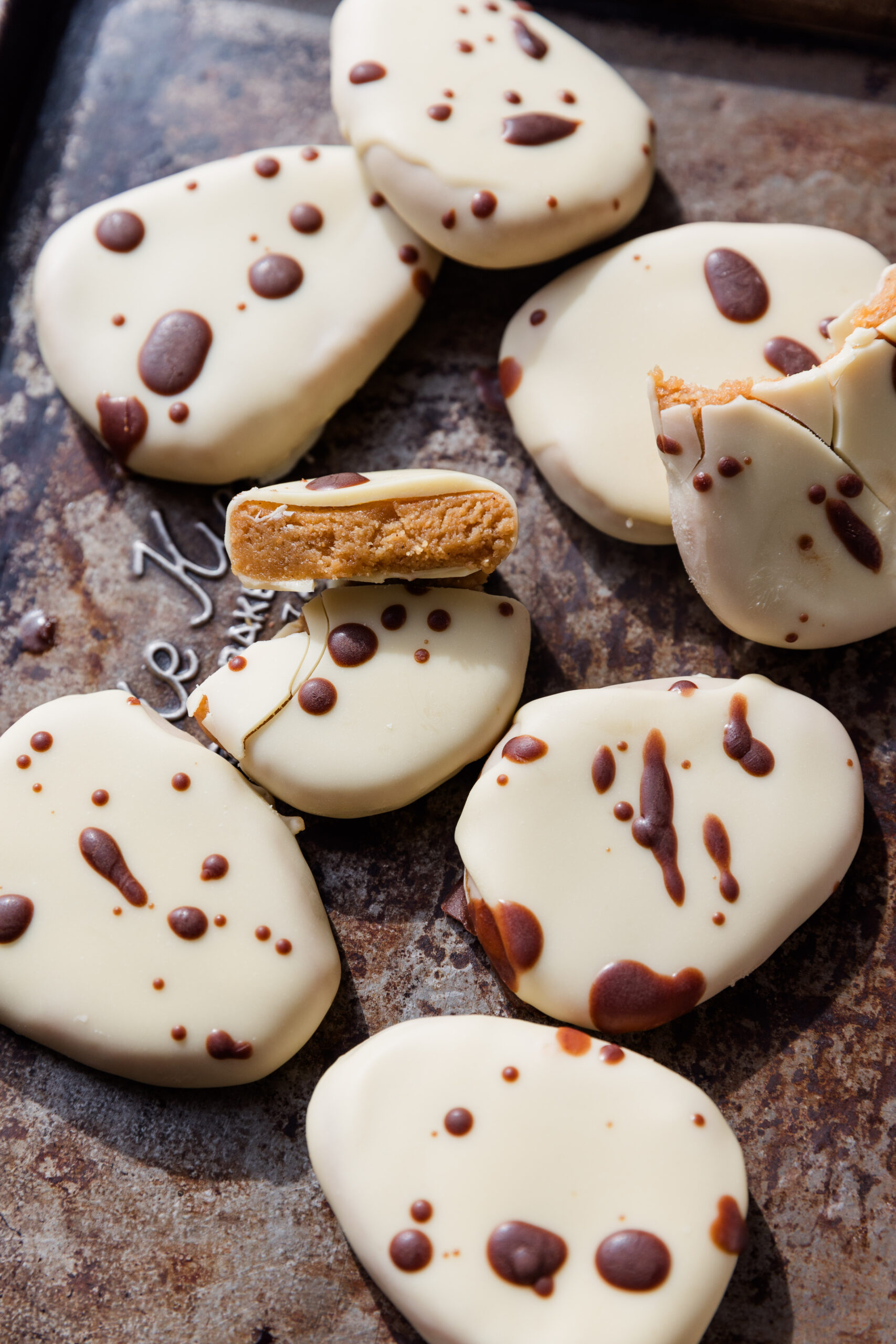 White chocolate covered copycat healthier Reece's eggs on a baking sheet with dark chocolate drizzled on top.