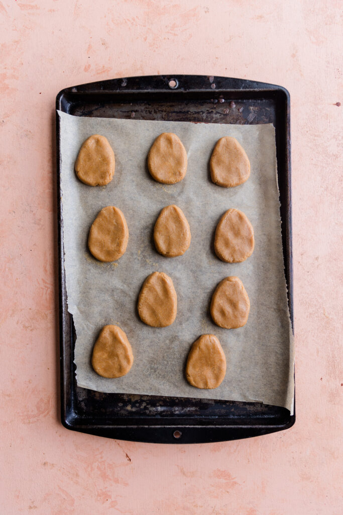 The filling is shaped into 10 eggs on parchment paper.